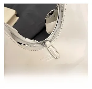 Detail of silver zipper and white patent leather bag with embossed logo lettering