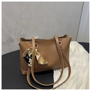 Detail of a brown leather tote bag featuring a decorative vintage chain print silk scarf