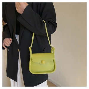 Fluorescent green crossbody leather bag with round buckle shown on a female model