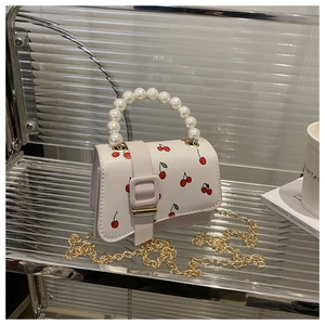Detail of white cherry print mini bag with pearl handle and golden chain strap