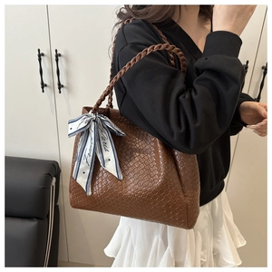 Détail d'un sac cabas marron tissé avec poignée tressée et foulard en soie décoratif