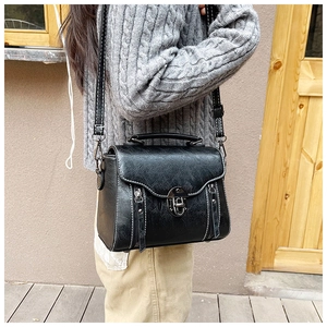 Detail of black vintage crossbody bag with white contrast stitching and metal twist lock