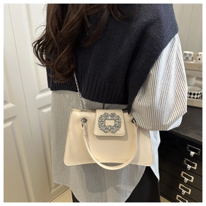 Dettaglio della borsa in pelle beige con fibbia quadrata di cristalli e catena metallica argento