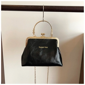Dettaglio di borsa vintage in pelle nera con chiusura a scatto e catena dorata