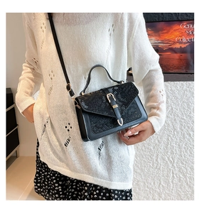 Detail of vintage black square bag with snake pattern embossing and gold buckle clasp