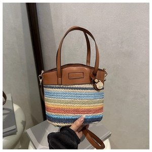 Détail d'un sac seau tissé multicolore avec bandoulière en cuir marron de qualité