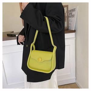 Detail of lime green leather shoulder bag featuring a large minimalist round buckle