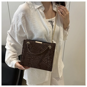 Detail of dark brown snakeskin textured crossbody bag with gold circular handle and chain