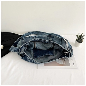 Flat lay of blue denim tote bag interior showing metal zipper and inner pocket details