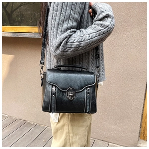 Detail of a vintage black crossbody bag featuring contrast stitching and a metal twist lock