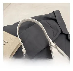 Detail of white leather shoulder bag featuring a silver metal heart chain pendant and slim strap