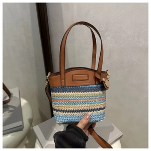 Détail du sac seau en paille color-block avec textures tissées et poignées en similicuir chic