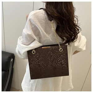 Detail of snake-embossed brown shoulder bag with gold metal bar and chain strap for women