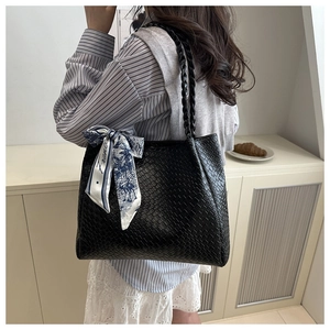 Vue détaillée du sac cabas en cuir tressé noir avec un foulard en soie imprimé décoratif