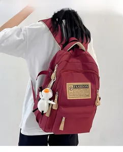 Burgundy nylon backpack with multi-zipper pockets and cute white duck plush accessory