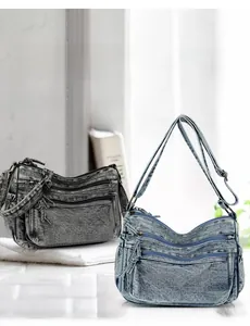 Close-up of denim shoulder bags in dark grey and light blue with multi-zipper pockets