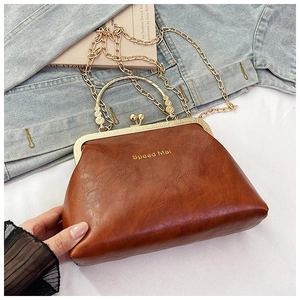 Dettaglio macro della borsa vintage in pelle marrone con telaio dorato e tracolla a catena
