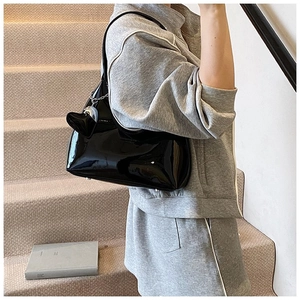 Close-up of black patent leather baguette bag featuring a unique cat-ear charm detail