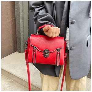 Detail of red vintage crossbody bag showing textured leather and retro twist lock