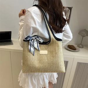 Straw tote bag with black leather trim and decorative silk scarf for summer beach trips