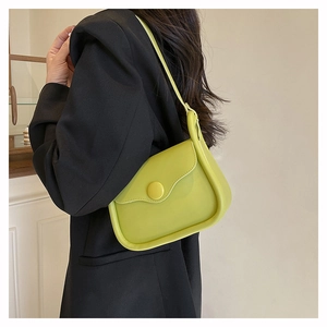 Detail view of a bright green crossbody bag with rounded design on a black blazer