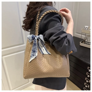 Détail d'un grand sac cabas tissé marron avec un foulard décoratif en soie sur la bandoulière