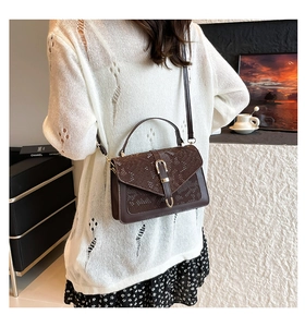 Detail of dark brown faux leather handbag with snakeskin pattern and buckle closure