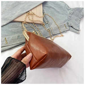 Dettaglio della chiusura in metallo vintage e catena dorata su borsa in pelle marrone