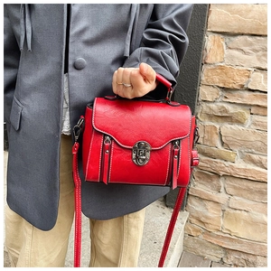 Detail view of red faux leather handbag with contrast stitching and metal twist lock