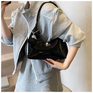 Close-up of black patent leather baguette bag featuring a silver heart charm
