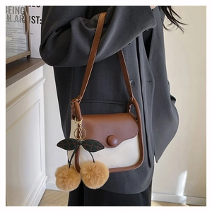 Detail of minimalist retro crossbody bag with cherry-shaped plush pompom charms