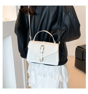 Model wearing a white crossbody bag with snake-embossed flap and gold horseshoe buckle