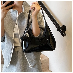 Detail shot of black patent leather hobo bag with silver heart charm and mirror finish