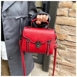 Detail of vintage red leather crossbody bag with white stitching and metal twist lock