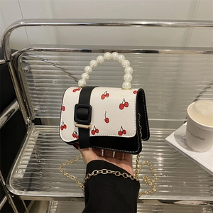 Mini handbag with cherry print and pearl handle held by model for lifestyle view