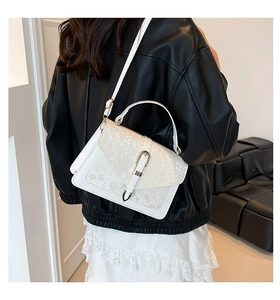 Detail of white snakeskin texture flap handbag with metal buckle strap worn by model