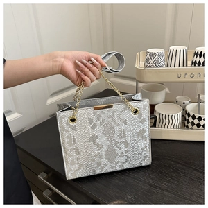 Detailed view of snake-print crossbody bag with golden chain handle and metallic hardware