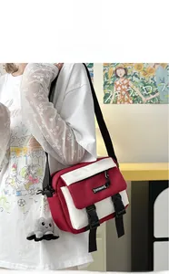 Detail of red and white canvas messenger bag with adjustable strap and octopus plush charm