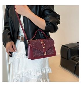 Detailed close-up of burgundy snake-embossed pattern and gold metal buckle on handbags