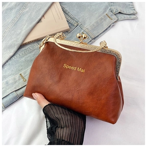 Dettaglio borsa vintage marrone con chiusura a scatto e manici in metallo dorato