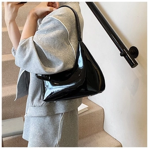 Close-up of black patent leather hobo shoulder bag with a glossy mirror finish