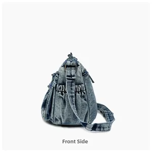 Side view of washed light blue denim shoulder bag featuring ruched pockets and metal rings