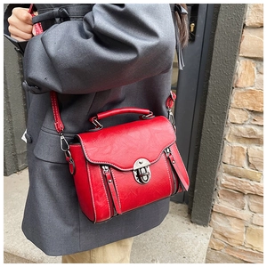 Detail of red vintage crossbody bag with white contrast stitching and silver metal buckle