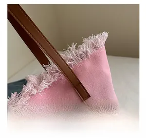 Detail of pink canvas tote bag featuring fringe edges and brown leather handle texture