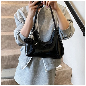 Detail of black glossy hobo bag featuring a silver heart charm and textured finish