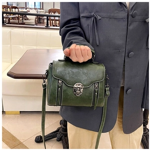 Detail of dark green vintage crossbody bag with metal twist lock and decorative zippers