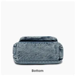 Detail view of the rectangular base of blue washed denim crossbody bag with edge stitching