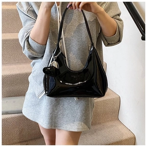 Detail of black glossy hobo bag featuring silver heart charm and metal chain strap