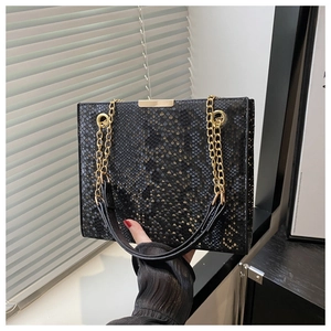 Close-up of black snake pattern small square bag with golden chain straps and metal clasp