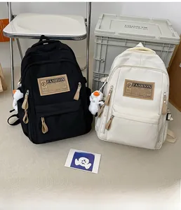 Detail of minimalist canvas backpacks in black and cream with cute plush duck pendants